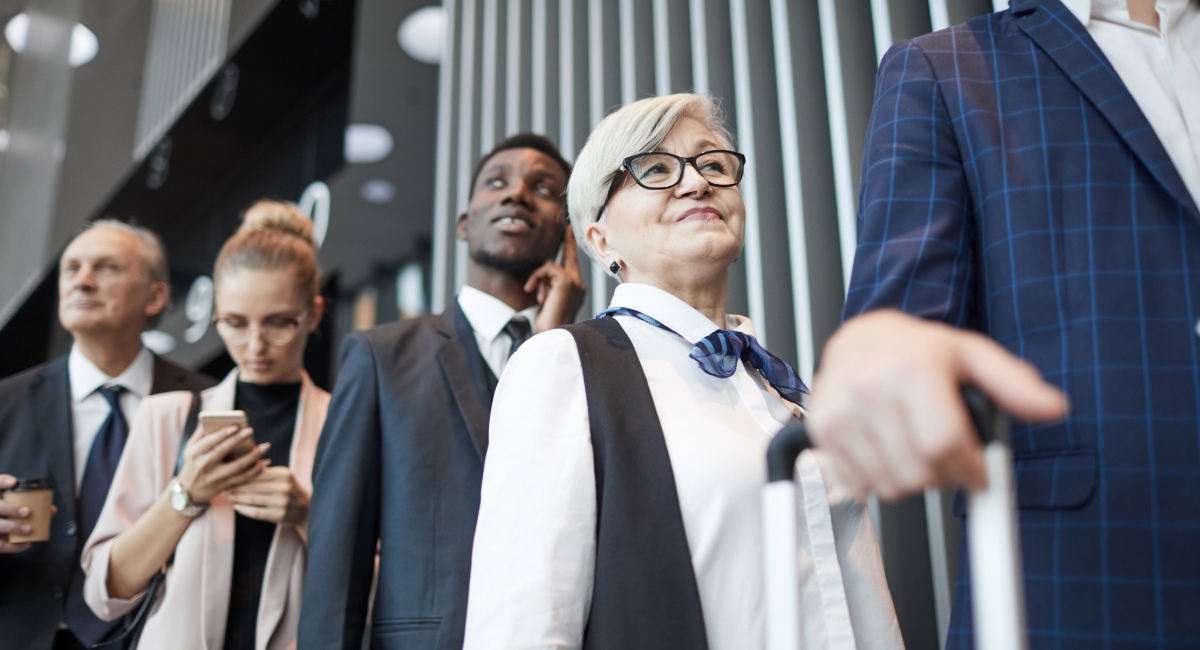 Professional business travelers with rolling luggage preparing for corporate travel risk assessment and safety protocols