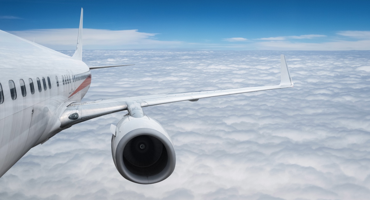 Commercial aircraft wing view during business flight demonstrating modern travel technology and risk management systems