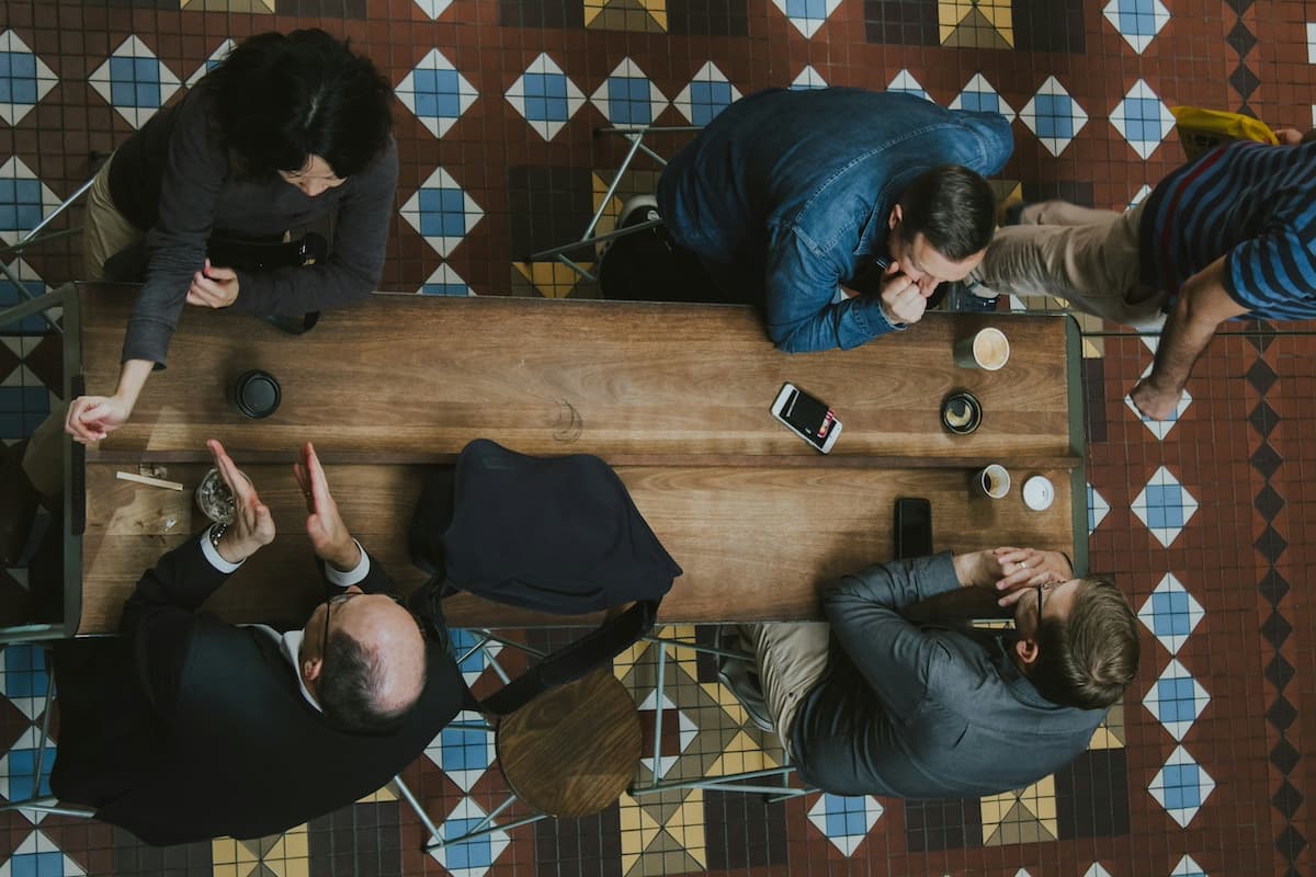 Four people sitting at a wooden table in a cafe talking
