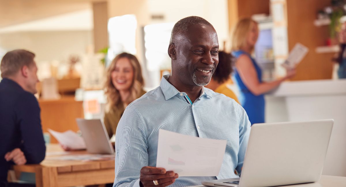 Mature Businessman With Laptop Working On Table In Office Coffee Shop