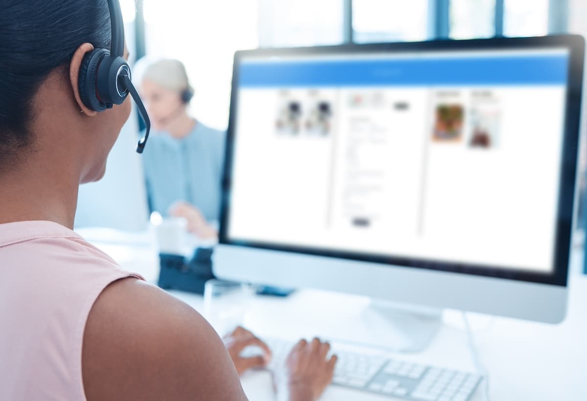 Online customer support worker wearing a headset sitting at a computer