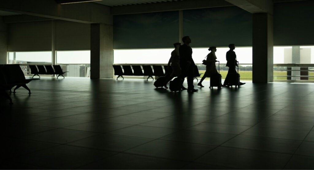Crew members walking through an airport terminal with luggage en route to a job site