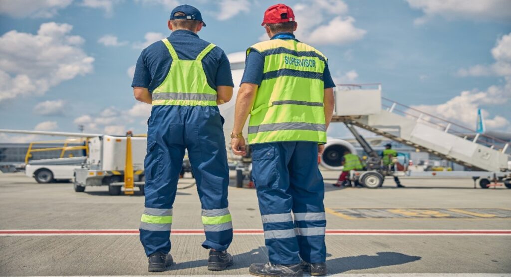 Oil and gas crew transport supervisor and ground worker in hi-vis gear at an airport tarmac