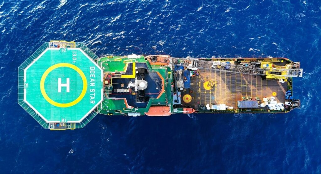 Aerial view of an offshore oil and gas vessel with helipad and equipment deck surrounded by open ocean