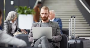 Business traveller reviewing expenses on laptop at airport gate