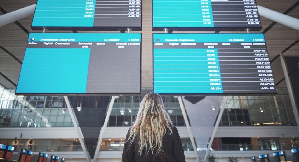 Woman, airport and back with schedule on monitor for flight, travel