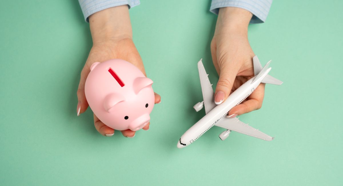 A Piggy bank and passenger plane with a green background being held by a person